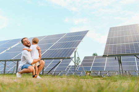 Smiling father and his little child on background of solar panels. Young father enjoy spending time...