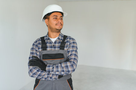 profession, construction and building - happy smiling Indian worker or builder in helmet over gray...