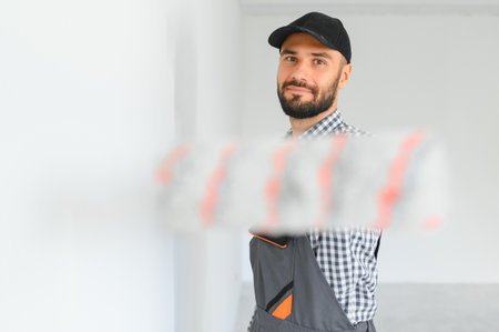 Young worker painting wall in room
