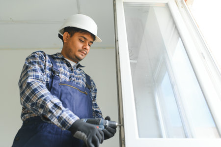 Indian Construction worker installing window in houseの写真素材