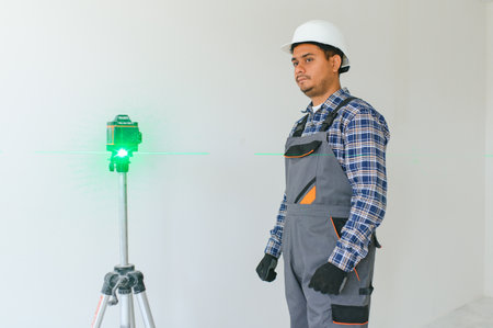 An Indian worker works in an empty apartment. A man in a uniform makes repairs inside the building.の写真素材
