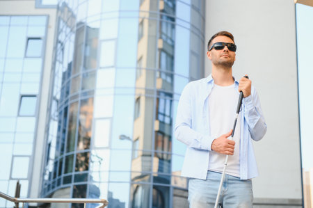 Young handsome blinded man walking with stick in town.の写真素材