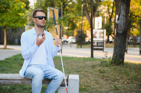 Young blinded man using phone and sending voice message.