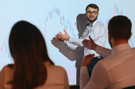 Man is standing near projector and showing graphs and business graphsの写真素材