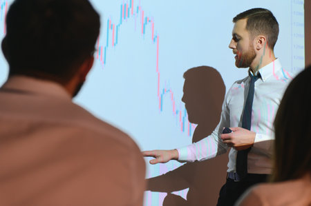 Young Businessman Explaining Graphs To His Colleagues On Projector.の写真素材