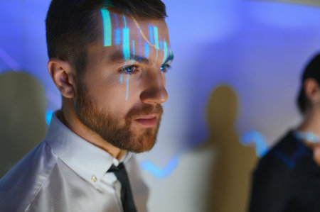 Stock Market Top Trader Looks at Projected Ticker Numbers and Graphs Running, Analyzing Data to Make Best Sell. Behind Him Room Full of Screens and Statisticsの写真素材