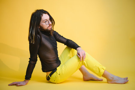 Young gay man is standing in the studio and posing for a cameraの写真素材