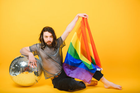Gay man hold rainbow striped flag isolated on colored background studio portrait. People lifestyle fashion lgbtq concept.の写真素材