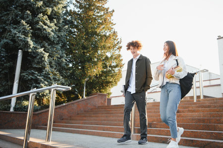 Front view of two students walking and talking in an university campusの写真素材
