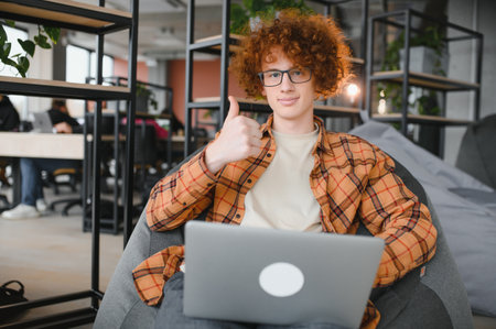 Great news. Male teenager expressing success in front of laptop at cafe, clenching his fist and yelling, copy spaceの写真素材