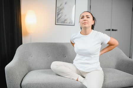Severe woman pain in head and neck while sitting on the couch at home