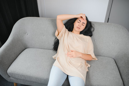 Young woman suffering from abdominal pain at home. Gynecology concept.の写真素材