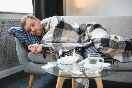 Sick man lying on sofa at homeの写真素材