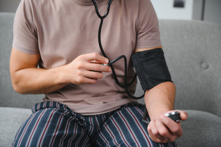 Young man measuring his blood pressure at homeの写真素材