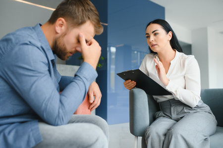 psychology, mental therapy and people concept - woman psychologist talking to sad young man patient at psychotherapy sessionの写真素材
