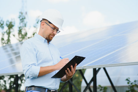 Engineer at solar power station with solar panel. Practical lessons on renewable energy power plantsの写真素材