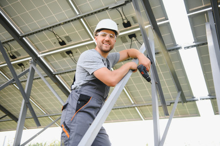 Male engineer in protective helmet installing solar photovoltaic panel system. Alternative energy ecological conceptの写真素材