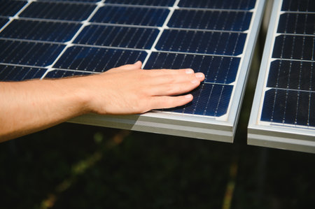 Close up of an young engineer hand is checking an operation of sun and cleanliness of photovoltaic solar panels on a sunset. Concept:renewable energy, technology, electricity, service, green, future.の写真素材
