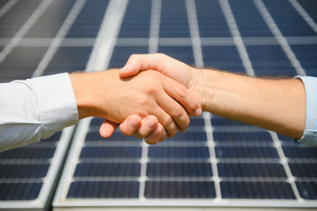 Workers shaking hands on a background of solar panels on solar power plant.の写真素材