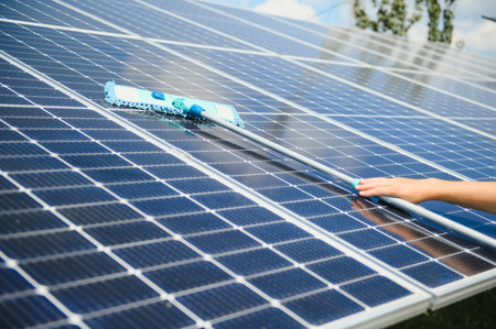 Worker cleaning solar panels after installation outdoors.の写真素材
