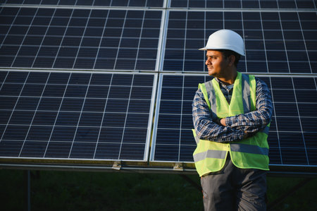 Male arabian engineer checking resistance in solar panels outdoors. Indian man working on station.の写真素材