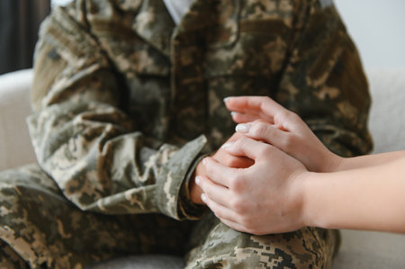 cropped shot of soldier and psychiatrist holding hands during therapy session