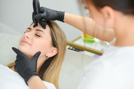 Young woman during procedure of permanent eyebrow makeup, closeupの写真素材