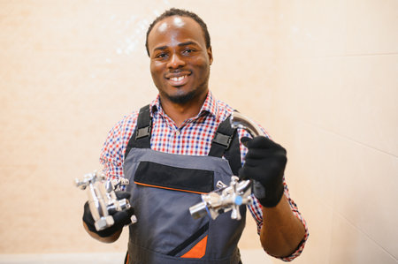 African american plumber holding faucet.