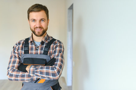 Portrait of a confident repairman with beard standing in empty apartment.の写真素材