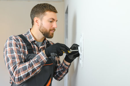 Electrician installs decorative frame on electric and TV sockets.の写真素材