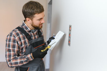 Electrician installs decorative frame on electric and TV sockets.の写真素材
