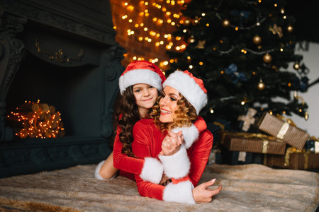 Mom and daughter are waiting for New Year presents near the Christmas tree.の写真素材