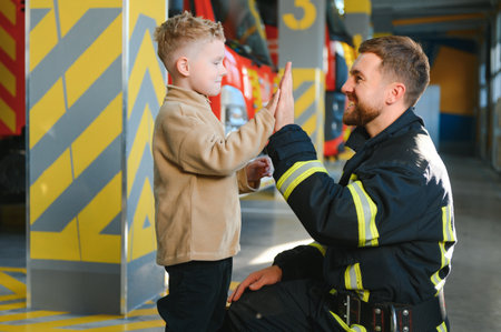 A firefighter take a little child boy to save him. Fire engine car on background.の写真素材