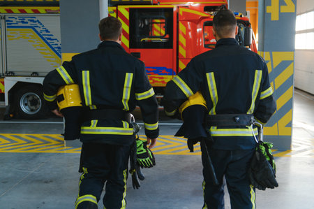 Two firefighters in protective clothing in helmets with fire engine.の写真素材