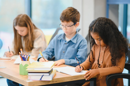 African American School Girl Writing Learning Sitting At Desk In Classroom Indoors. Diverse Children Having Class Taking Notes Indoor. Education And Knowledge. Selective Focusの写真素材