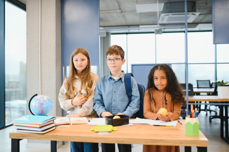 Multiracial schoolchildren having lunch at the desk during a break in school.