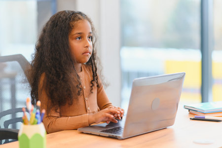 African american girl sitting at table, using laptop for online lesson.の写真素材