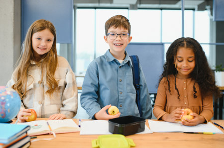 Multiracial schoolchildren having lunch at the desk during a break in school.の写真素材