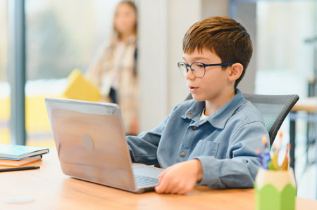 Smiling teen male chatting with friends in social networks sitting front laptop.の写真素材