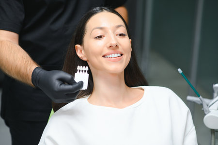 Dentist checking and selecting color of young woman's teeth.の写真素材