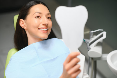 The girl smiles in dentistry. In the hands of the mirror.の写真素材