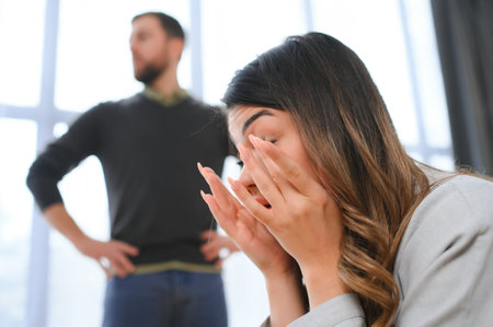 Irritated husband is shouting at his wife with violence. Woman is covering her face with fear.の写真素材