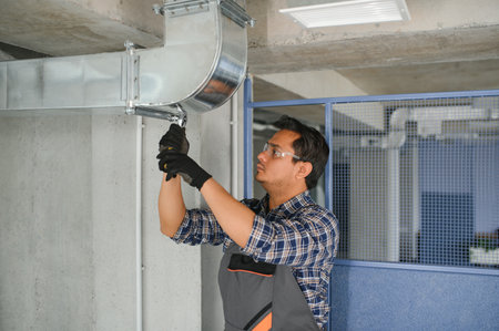 hvac indian worker install ducted pipe system for ventilation and air conditioning. copyspace.の写真素材