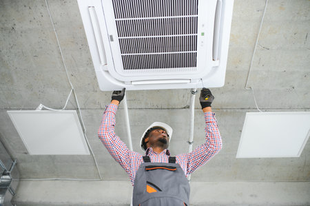Happy Young African Male Technician Repairing Air Conditioner.の写真素材