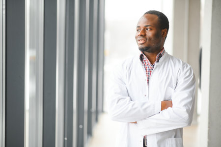 Portrait of young male doctor, standing against window at hospital corridor.の写真素材