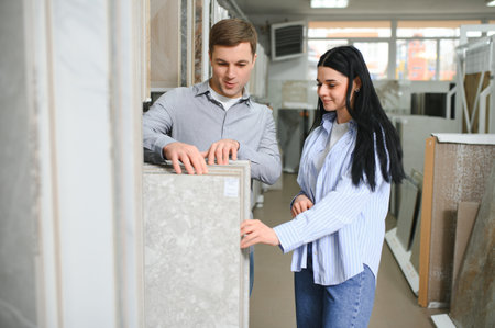 Beautiful young couple choosing ceramic tiles for their house renovation in the building shop.の写真素材