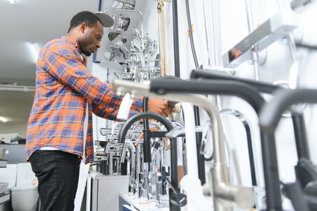 A large selection of water faucets. African American Man chooses a products in a sanitary ware...
