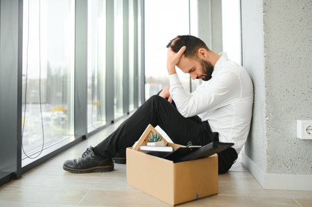 Fired frustrated man in suit sitting on floor in office.の写真素材