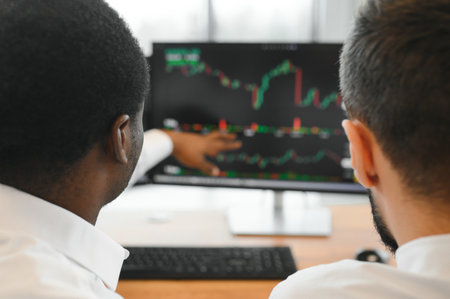 Two successful trader sitting in office, checking cryptocurrency information data on finance market...