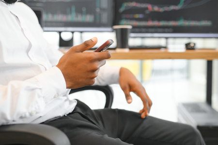 African American trader works at computer with displayed real-time stocks.
